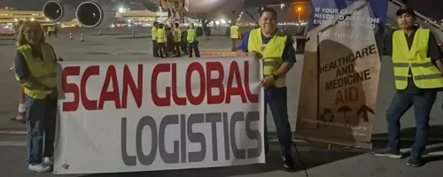 Scan Global Logistics team in front of a cargo aircraft, preparing to ship humanitarian aid during a tight emergency timeline